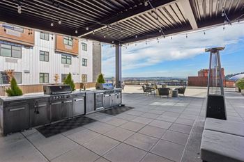 A rooftop patio with a grill and seating area.
